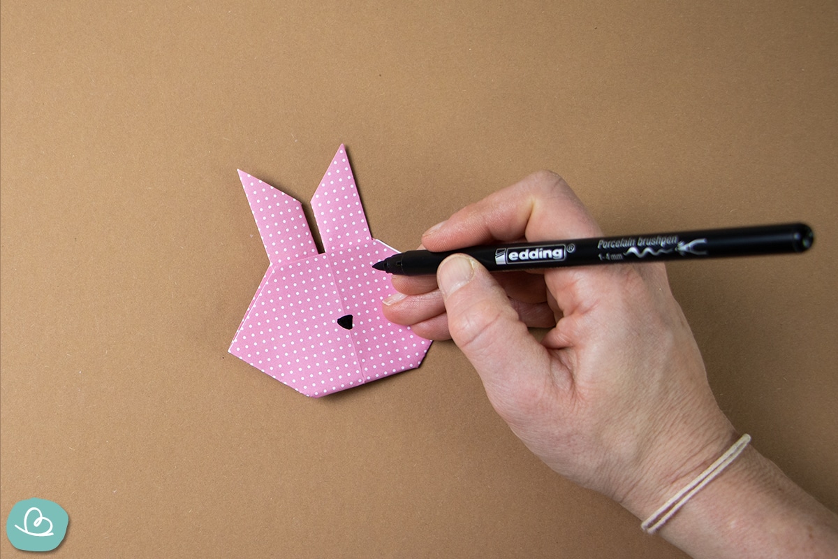Gesicht mit einem schwarzen Edding auf den Origami Hase zeichnen.