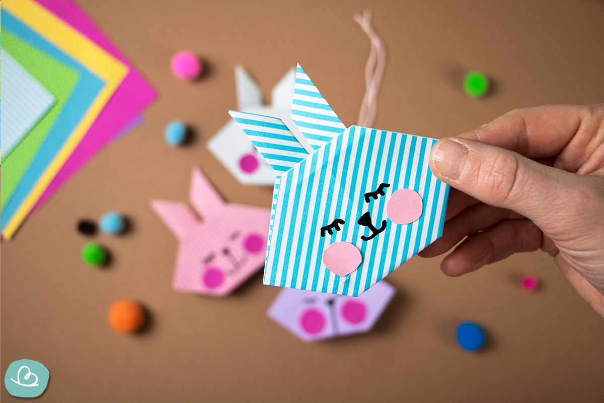 Origami Hase aus blau-weiß gestreiften Papier.