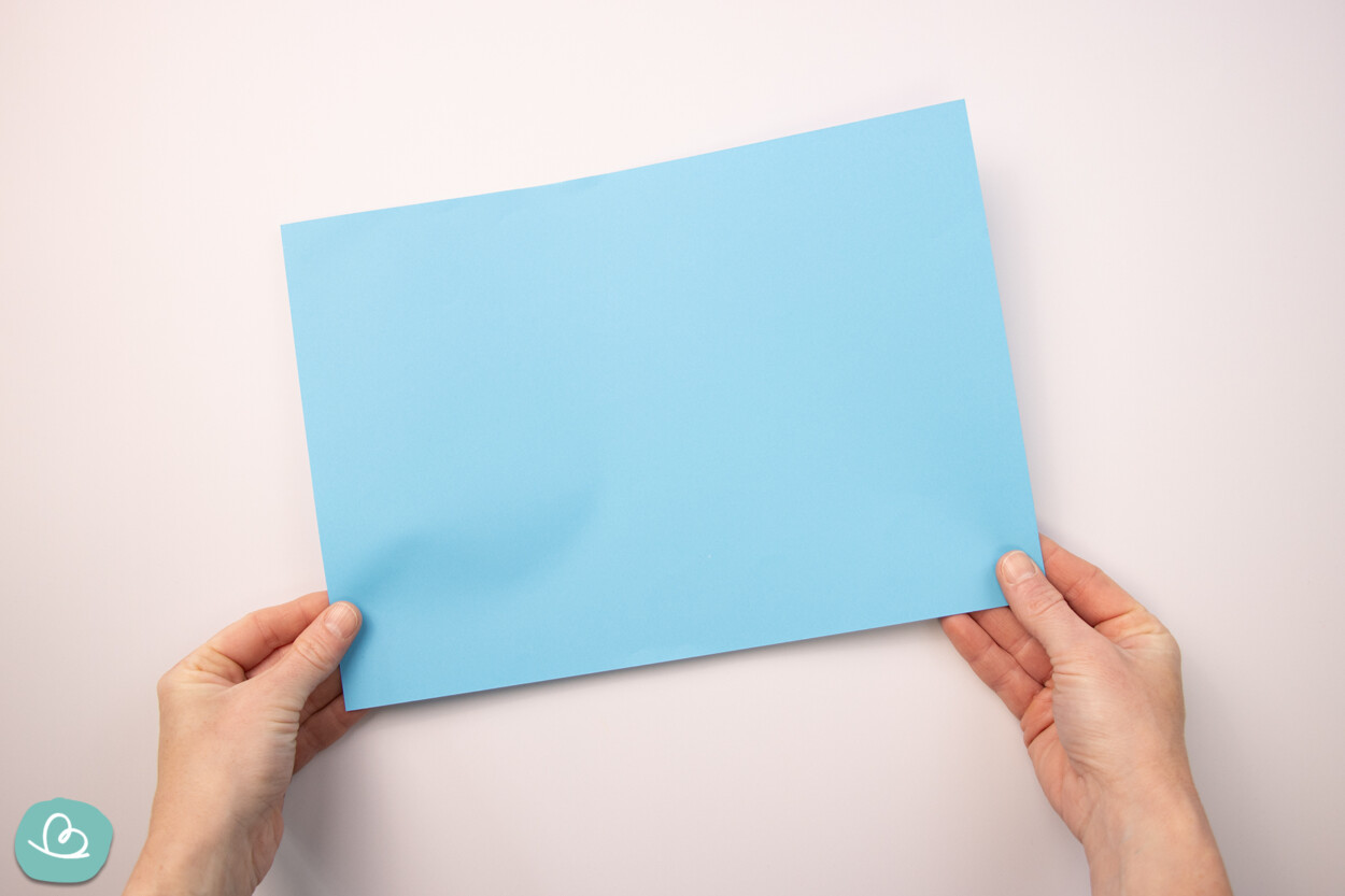 blaues Tonpapier in den Händen haltend