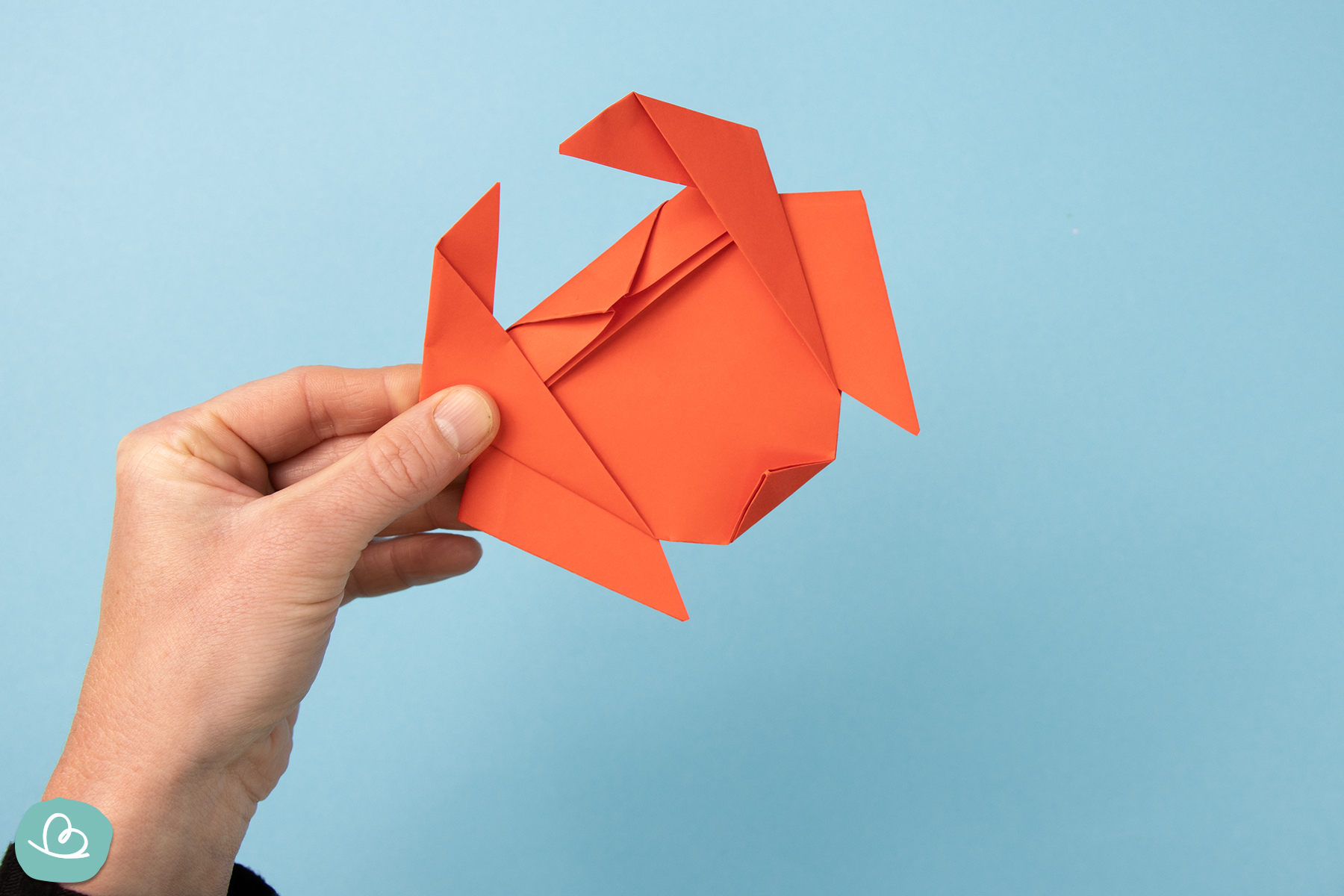 Ein fertig gefalteter Origami Krebs aus rotem Papier mit erkennbaren Scheren und Beinen