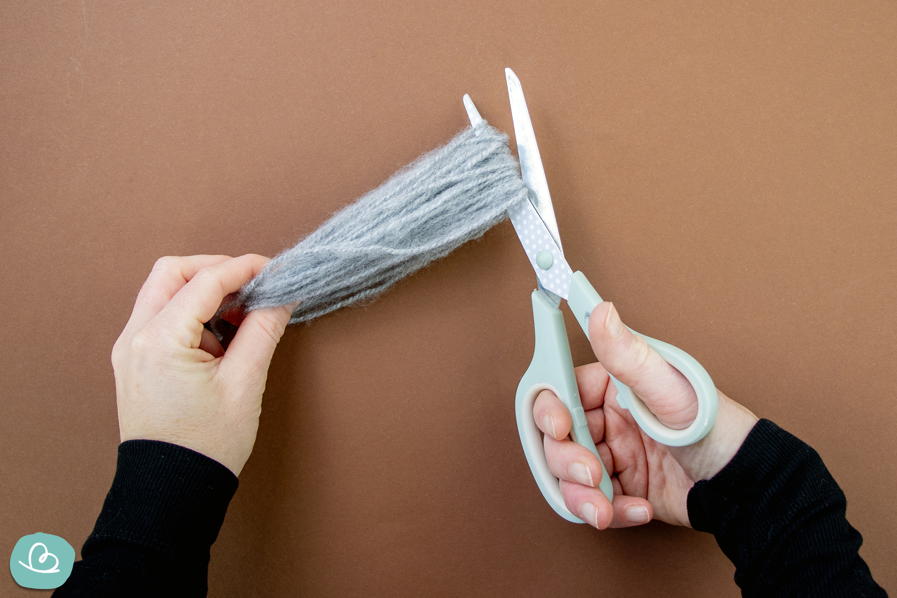 Wollknäuel mit einer Schere durchtrennen.