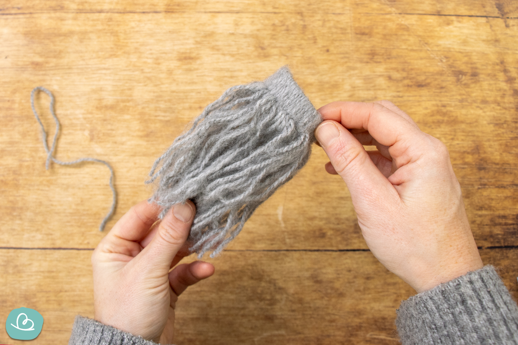 Wollfäden um Pappring geknüpft