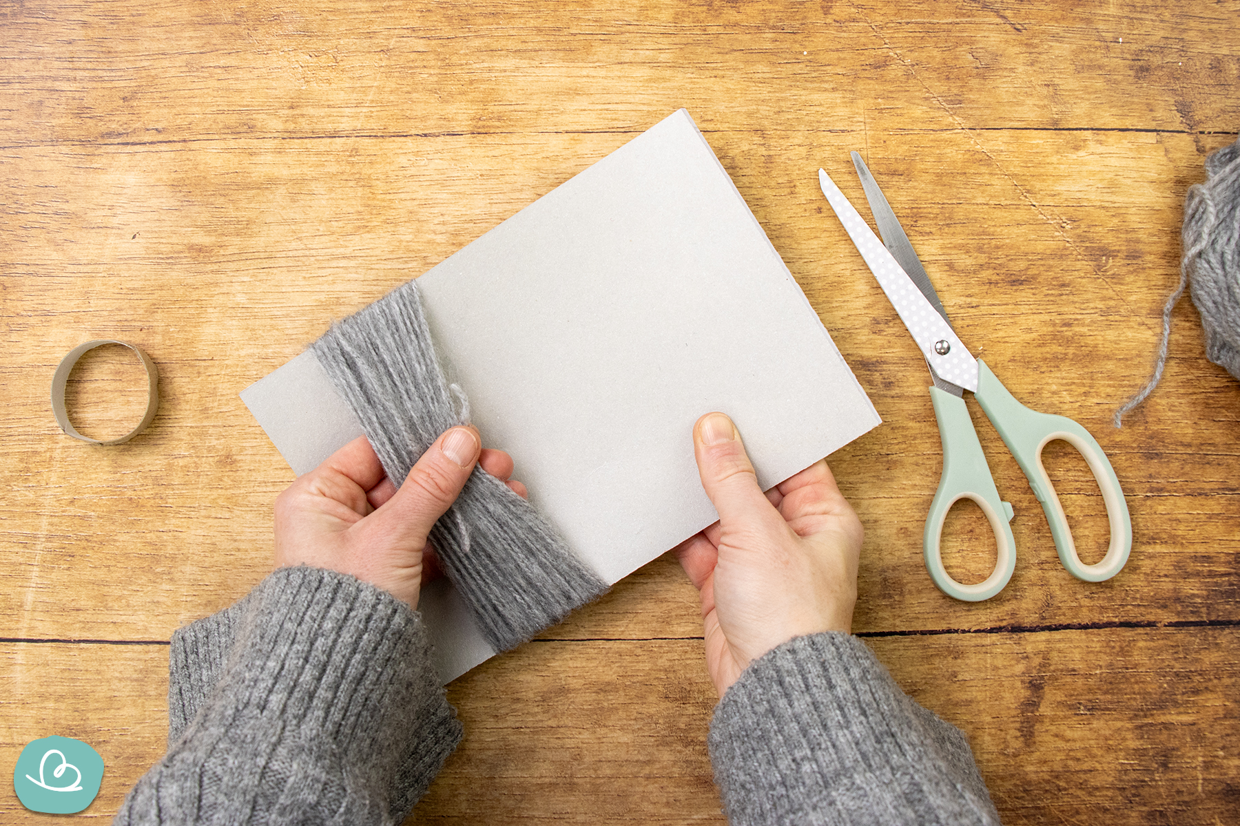 Aufgewickelte Wolle von Pappe abziehen